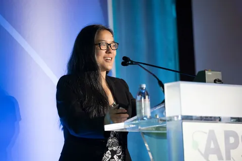Person standing at a podium and speaking into a microphone.