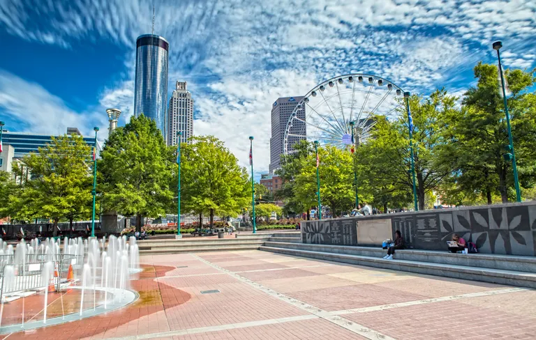 A plaza with a fountain and a Ferris wheel.