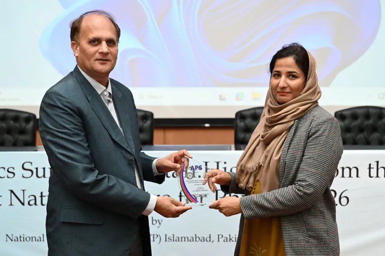 Two attendees exchange an APS award at a satellite site in Pakistan.