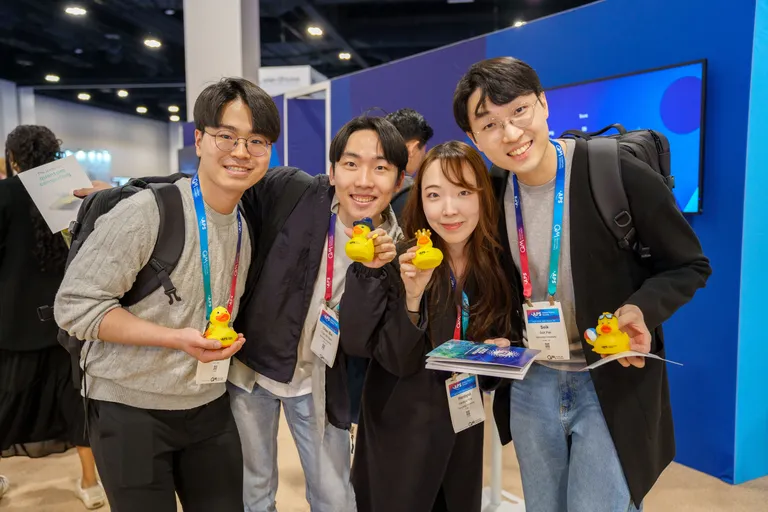 A group of conference attendees smiling for a photo and holding rubber ducks.