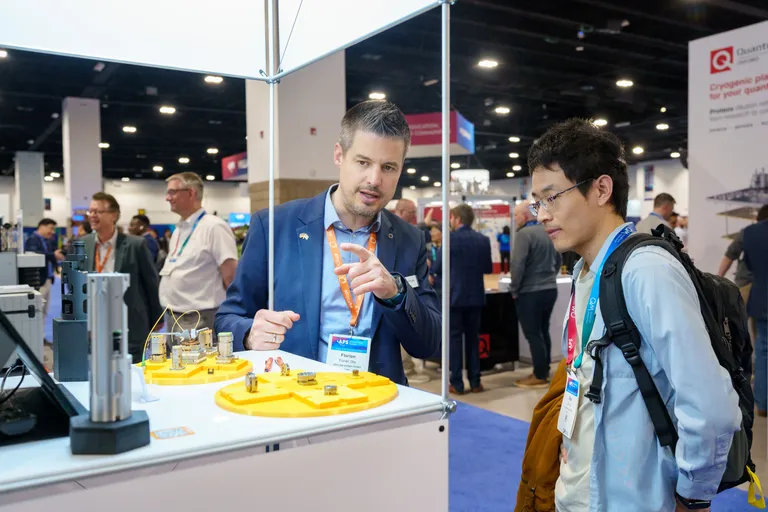 Two participants converse at an exhibit hall booth.